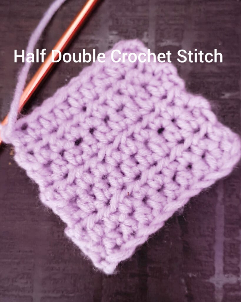 Purple crochet swatch made with half double crochet stitches, with a hook attached.