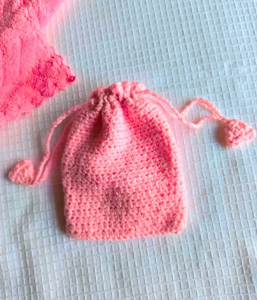 crochet-drawstring-bag A pink crochet bag closed with a drawstring. It has a white background.