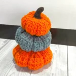 3 pumpkins are stacked on each other placed on a white table with brown and white background