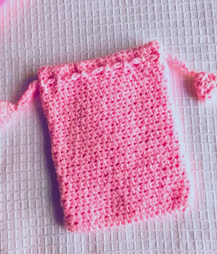 Pink colored crochet drawstring bag on a white background