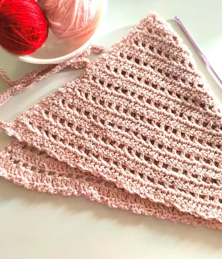 A crochet bandana placed with a crochet hook and yarn