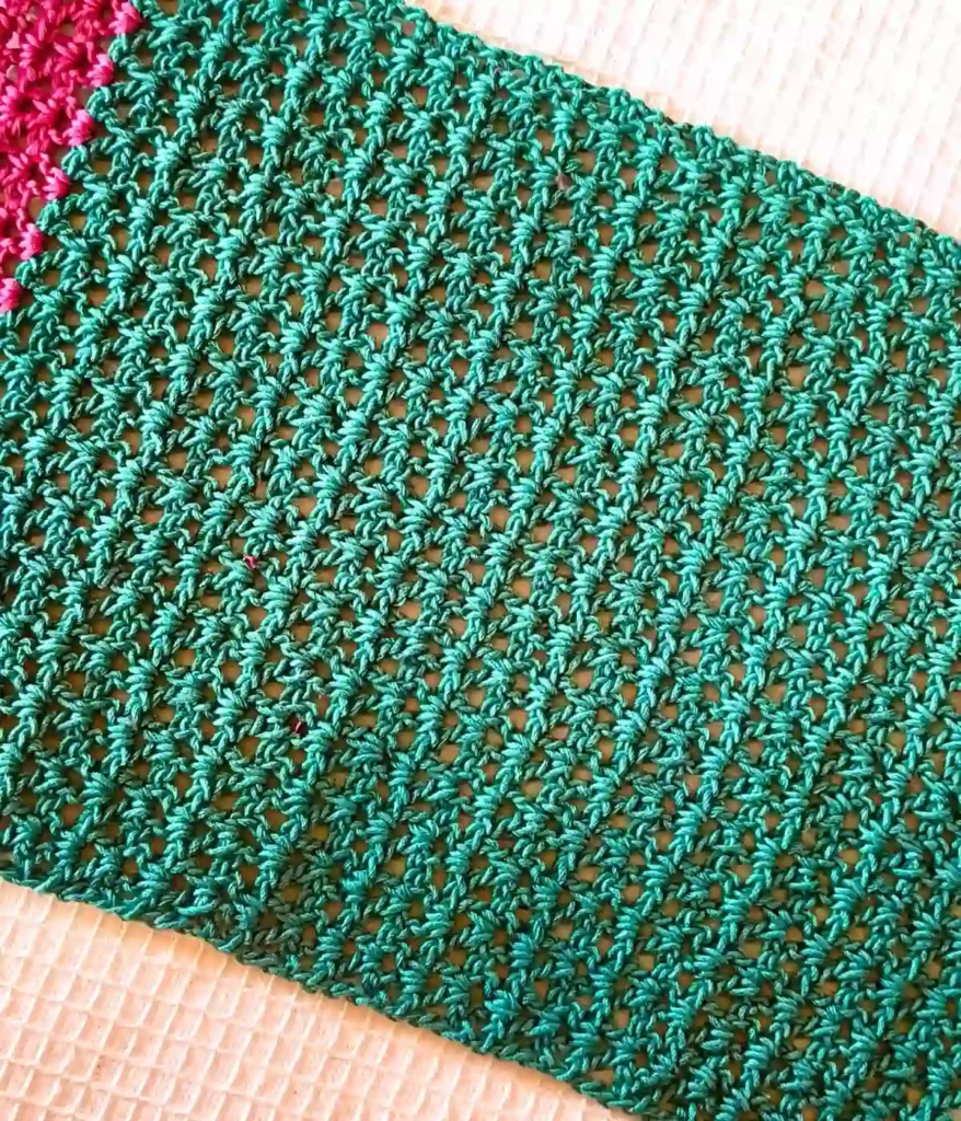 A close angle of a crochet v stitch green colour placemat, place on a white background
